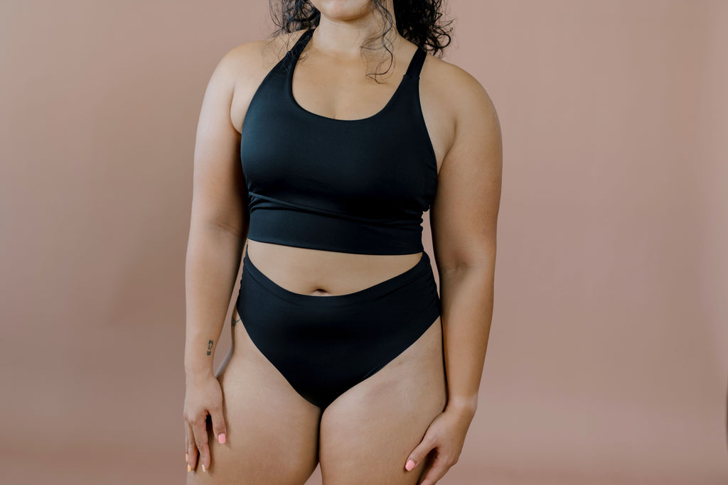 Person wearing a black brazilian briset against a beige background